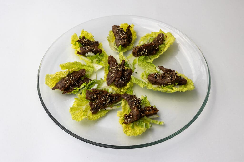 Steak spread on iceberg lettuce wedges with sesame seeds on top
